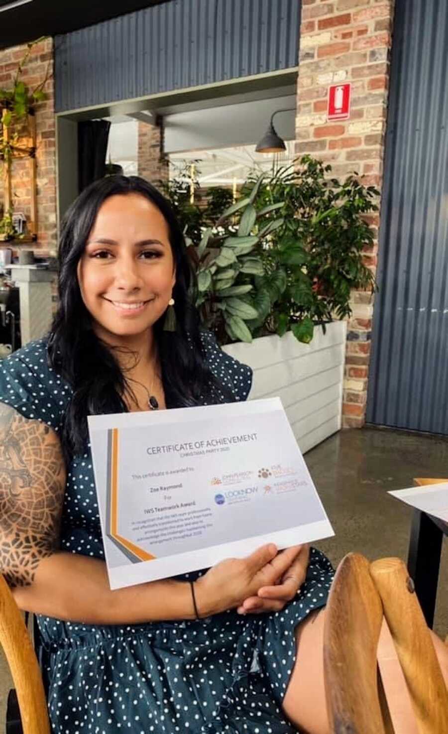 Aboriginal woman sitting and holding an achievement certificate