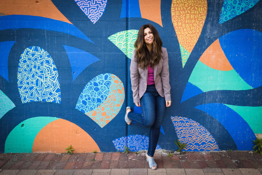 Divorce coach poses smiling in front of a grafitti wall