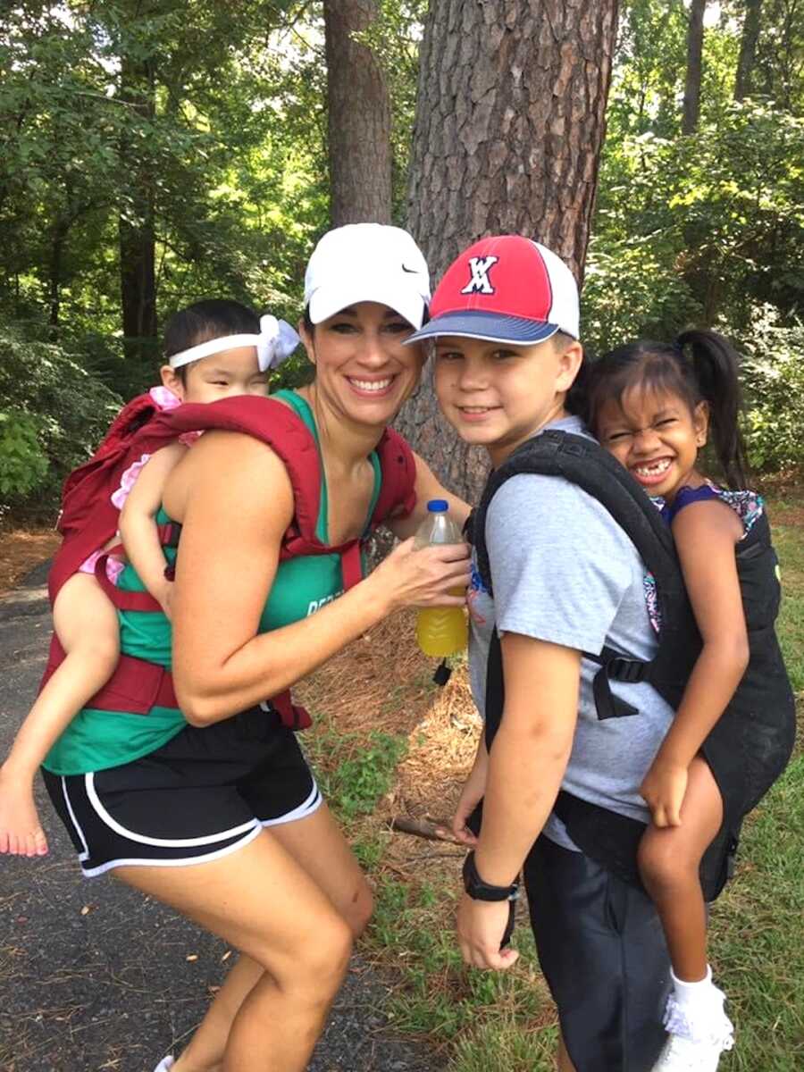 mom and son wearing backpacks that hold two adopted daughters