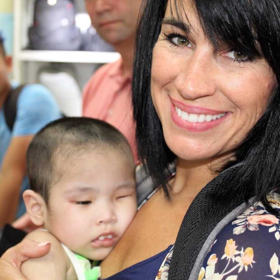mom holds adopted daughter close to her chest and smiles