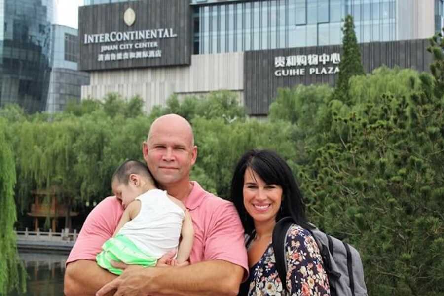 parents stand holding their newly adopted daughter who has special needs