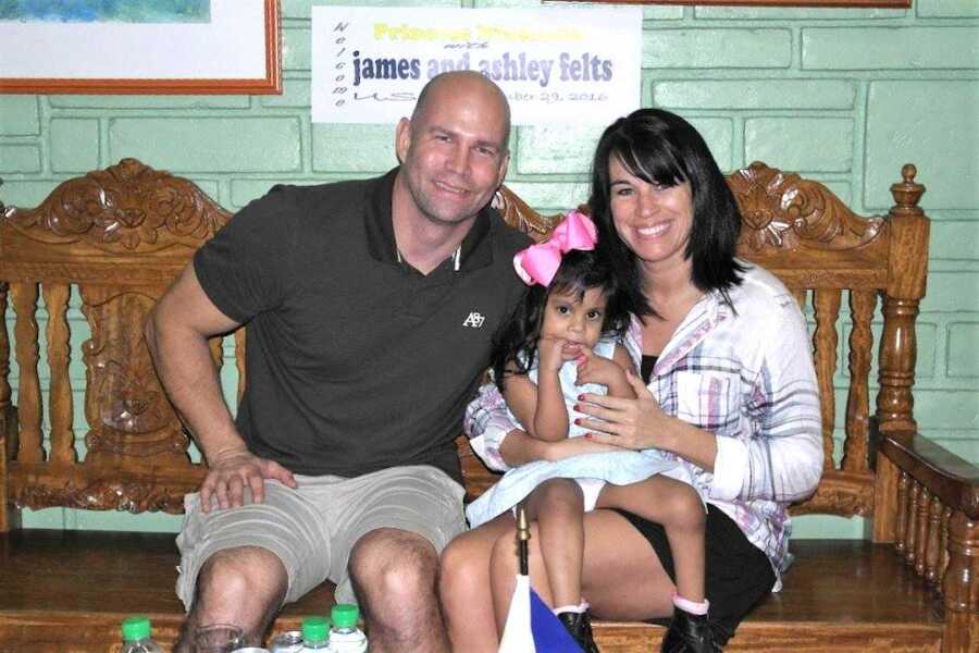 adoptive parents sit with their special needs daughter on their lap on adoption day