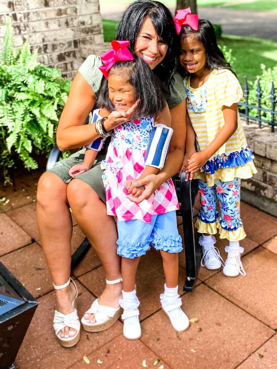 mom sits surrounded by her two adopted daughters