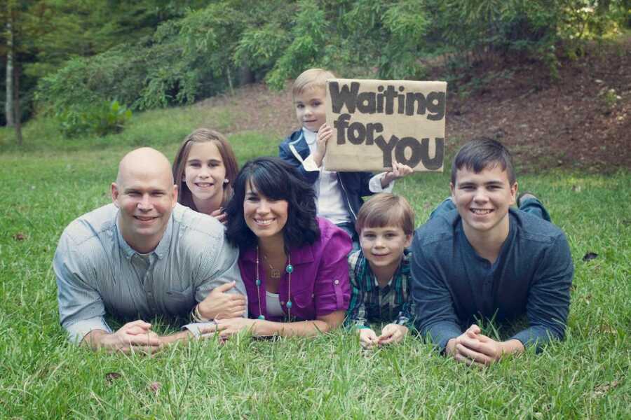 family lays on their stomachs together for their first adoption announcement