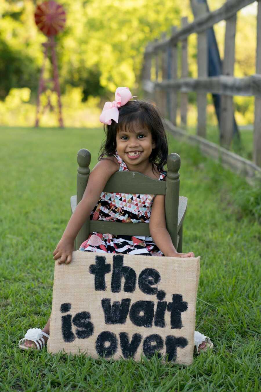 adopted daughter holds adoption announcement sign saying "the wait is over"
