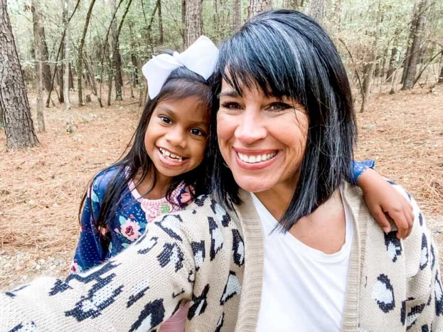 mom and adoptive daughter smiling with heads close to one another