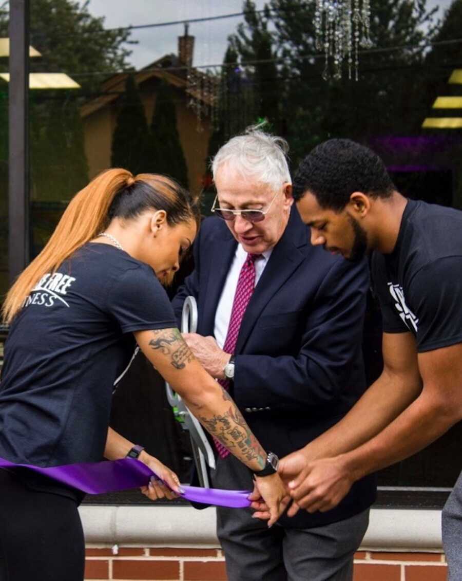 Fitness instructor helps cut the ribbon on her new gym with two men