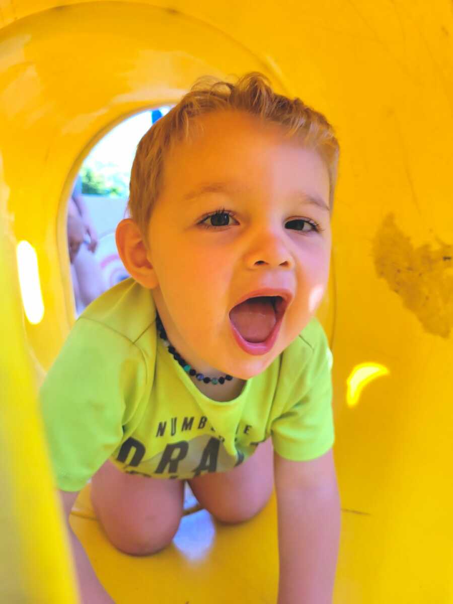 young boy plays on slide, makes a silly face
