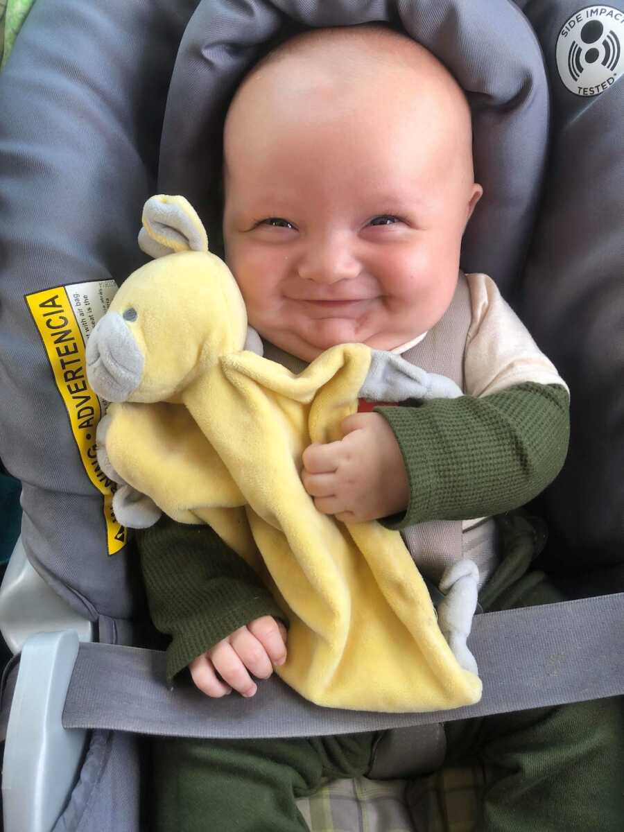 baby smiles while sitting in his car seat