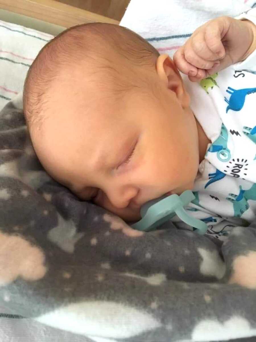 baby boy sleeps peacefully with binky in moth