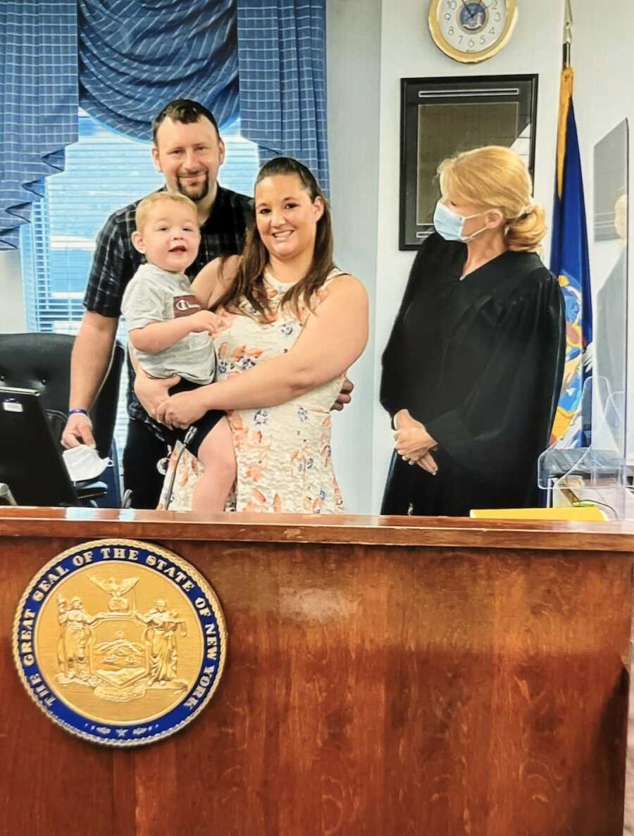 Mom holds her adopted son while in court on his adoption day