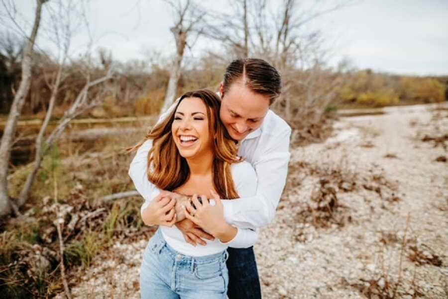 A man holds his wife as they stand outdoors