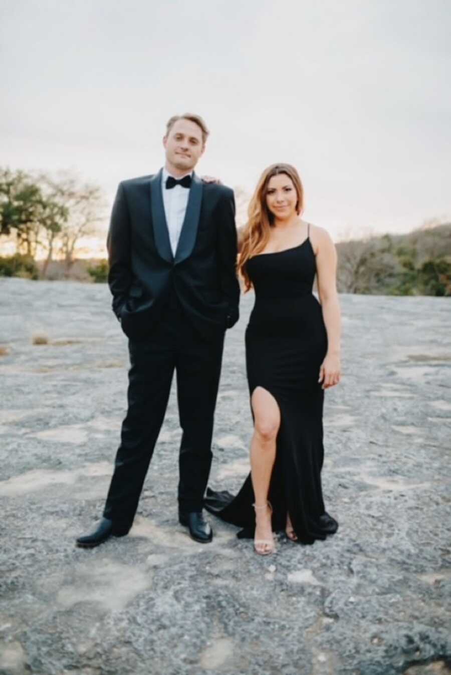 A woman and her husband stand outside wearing black