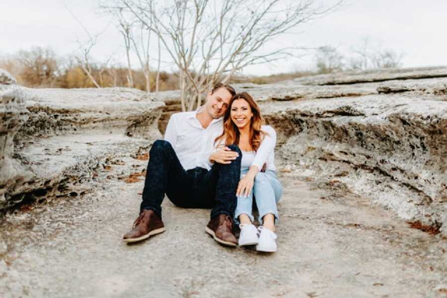 A woman and her husband sit outside near rock formations