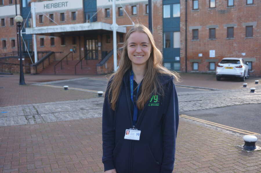 girl in eating disorder recovery stands wearing a badge and smiles