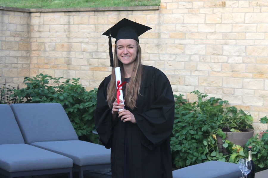 girl wearing cap and gown, holding a diploma