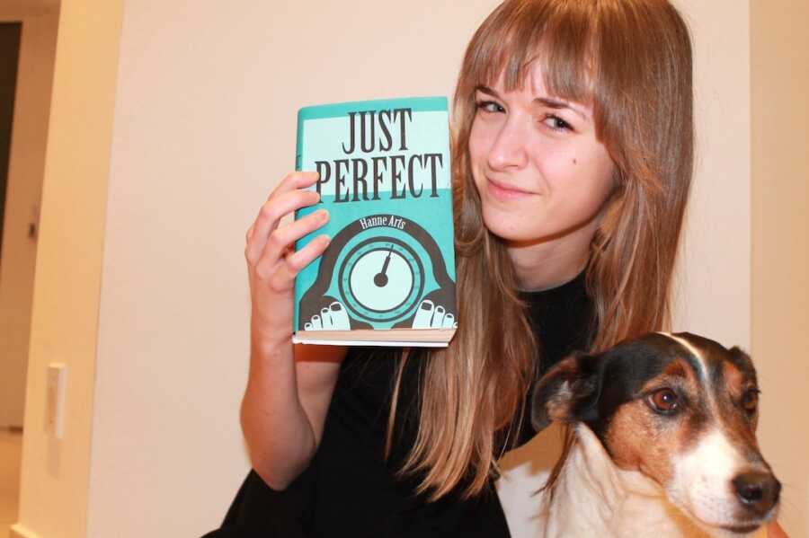 girl sits with her dog and a book titled "Just Perfect"