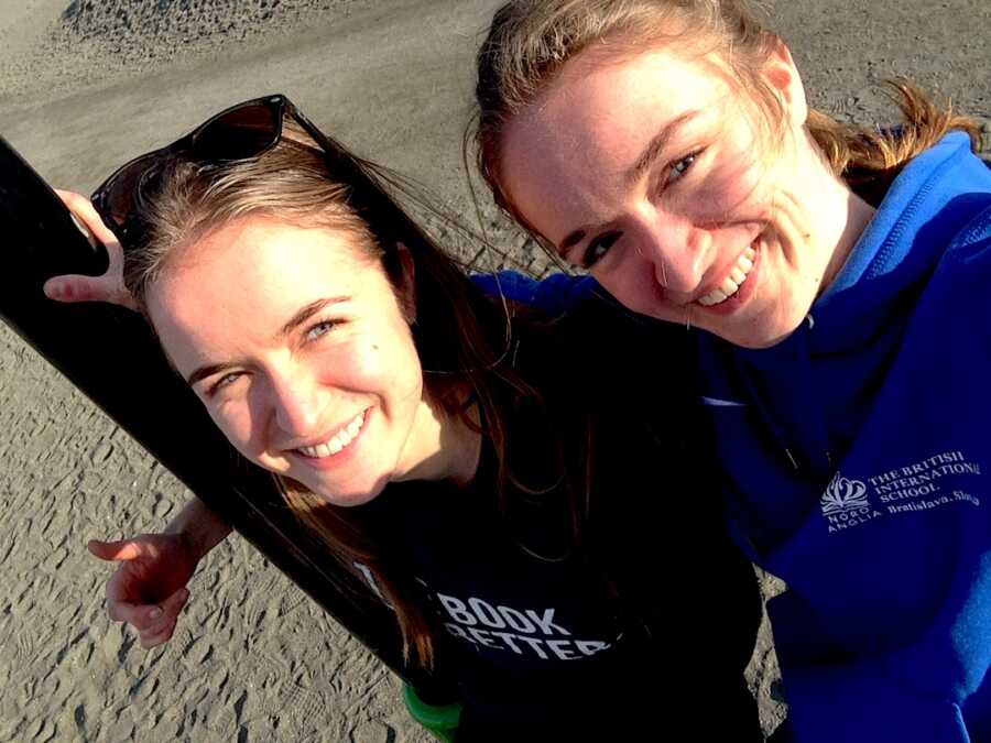 two young girls smile wide while on the sand