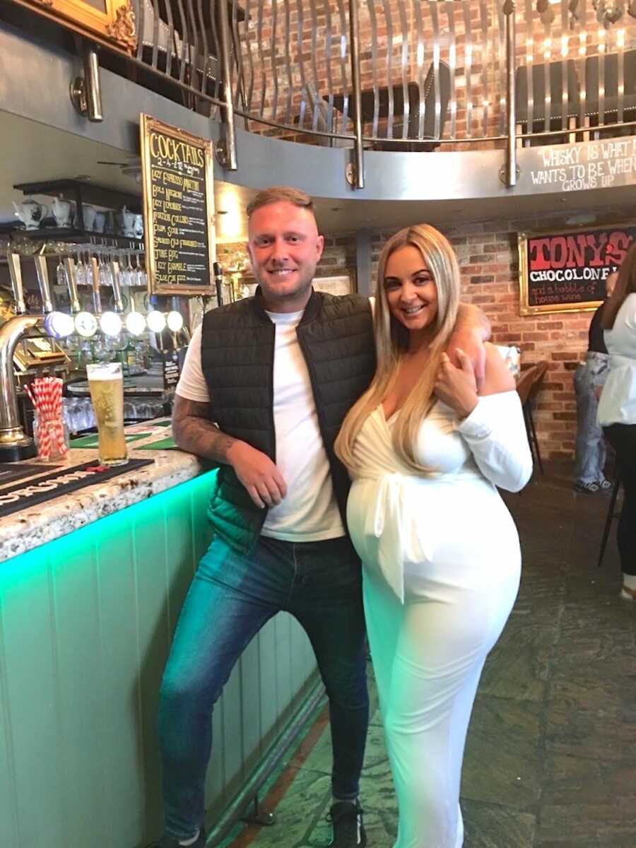 husband wraps arm around his pregnant wife