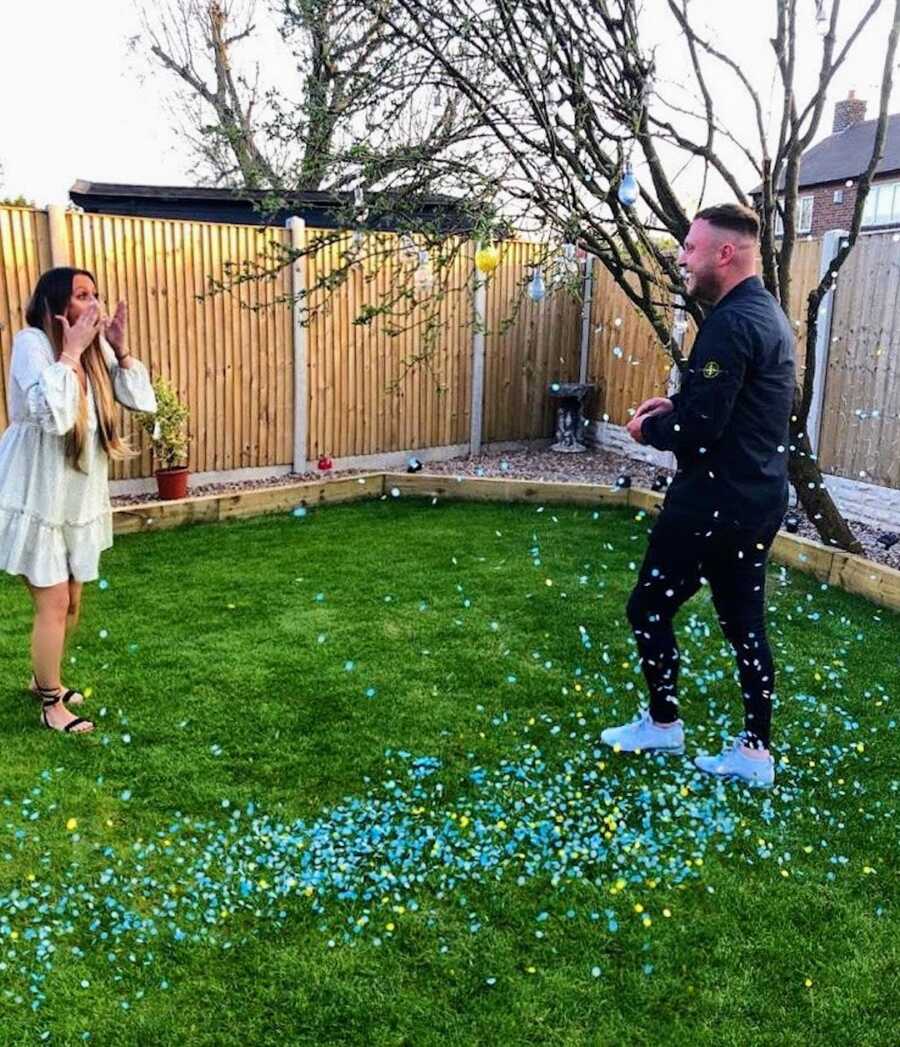 husband and wife at gender reveal party with confetti revealing they are having a boy