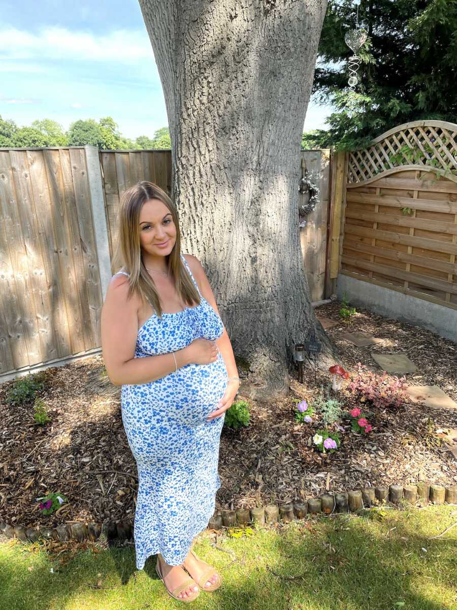 pregnant woman holds her belly while smiling