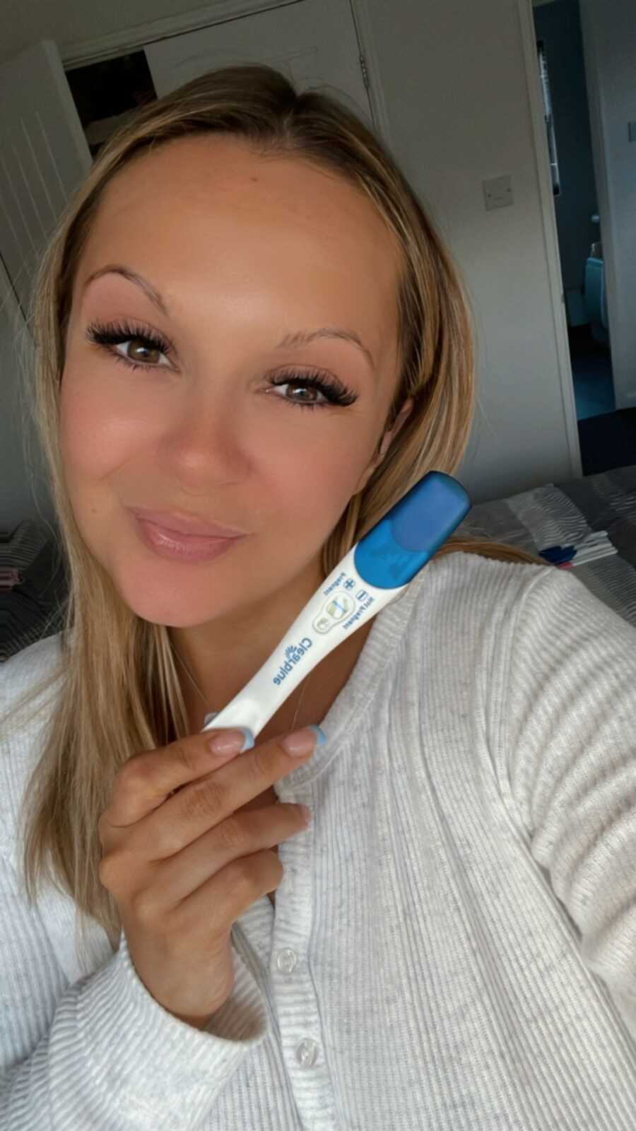 woman holds up positive pregnancy test