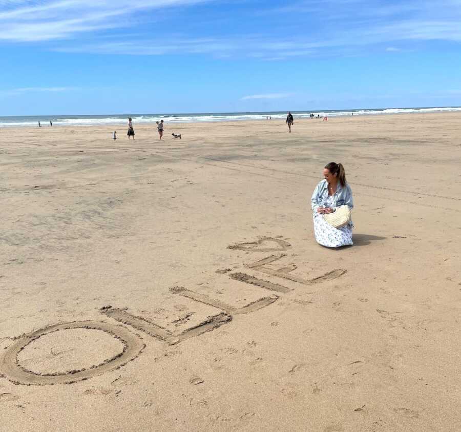 loss mom writes out baby's name in sand for remembrance