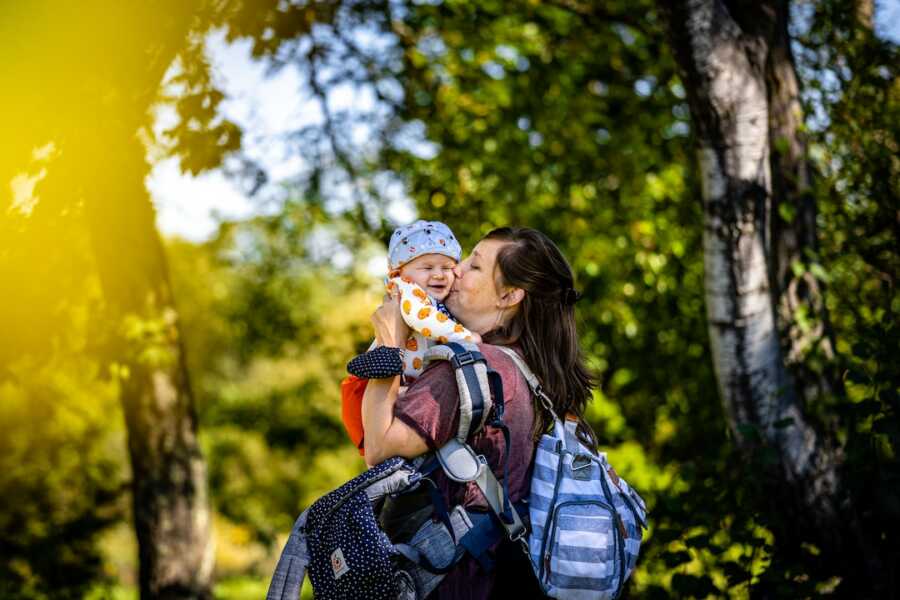 mom holds her baby close while carrying bags