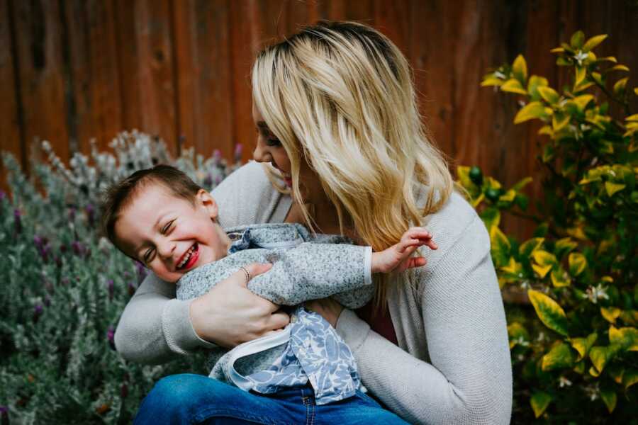 mom holds her son both are laughing