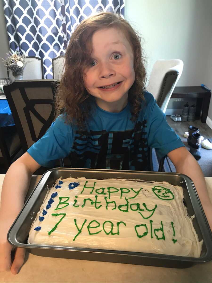 little boy with birthday cake in front of him 