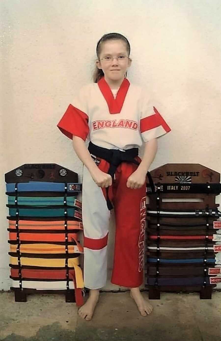 little girl taking a picture with her karate belts
