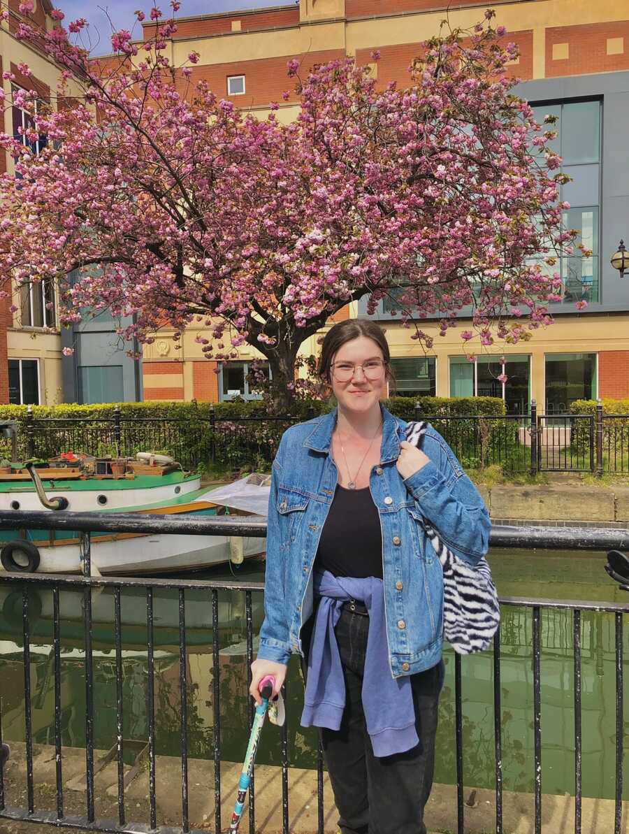 woman with disabilities (hEDS) in front of a cherry blossom tree 