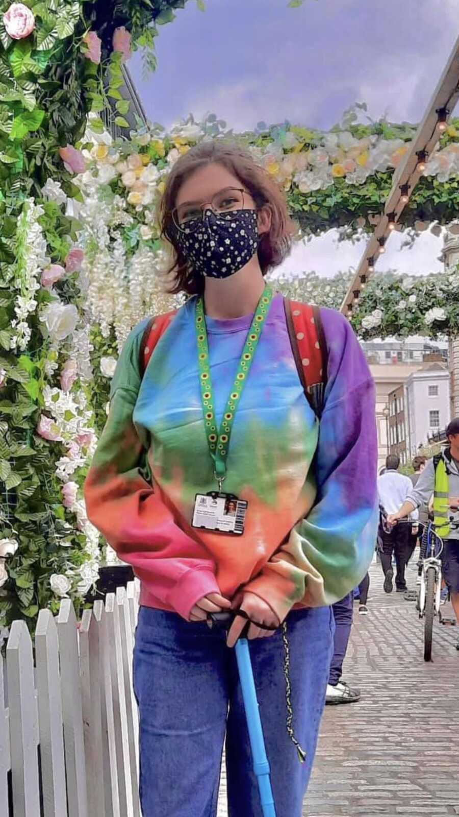 woman in a tie dye shirt amongst flowers