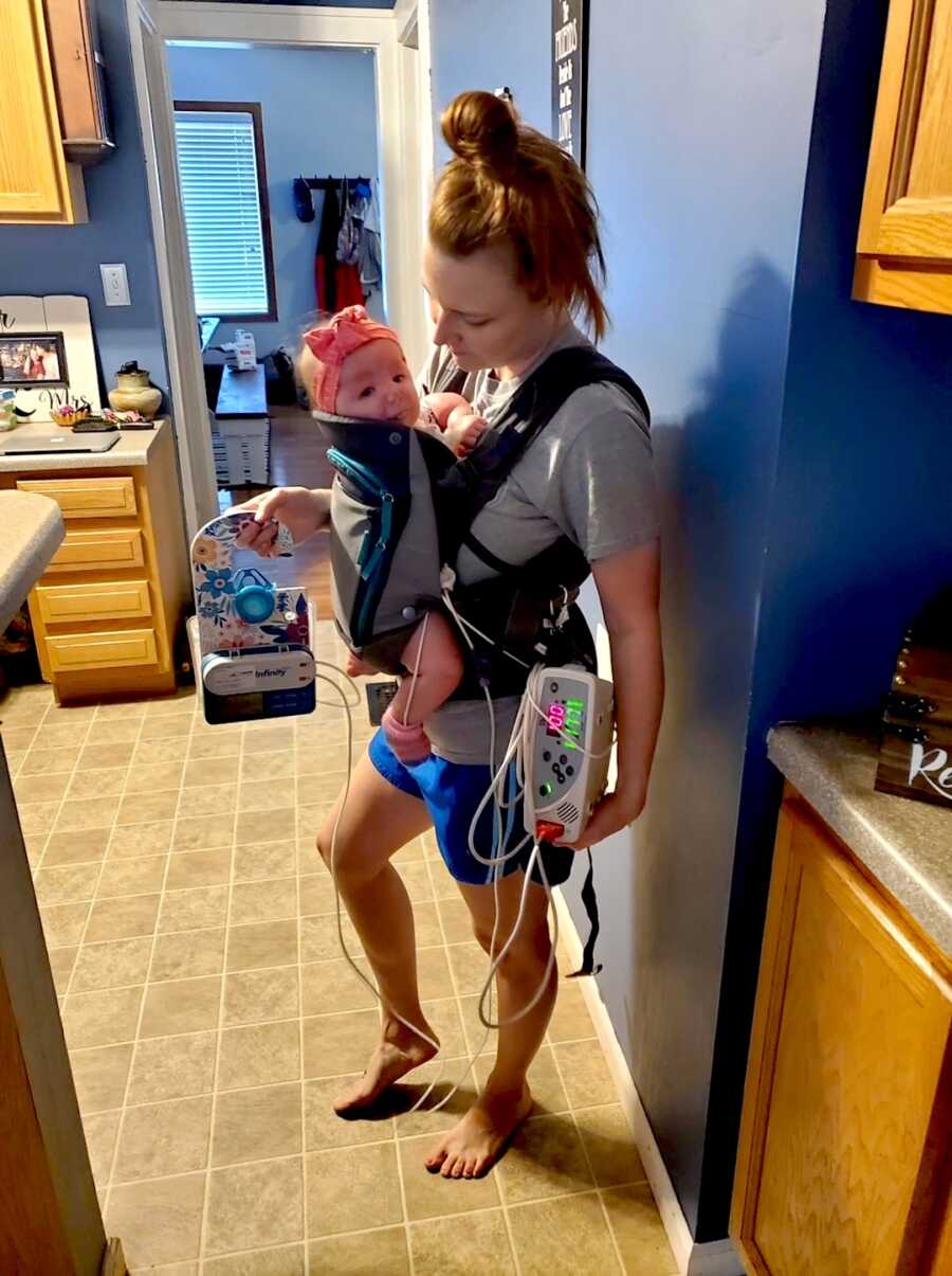 mom holds baby girl in chest carrier