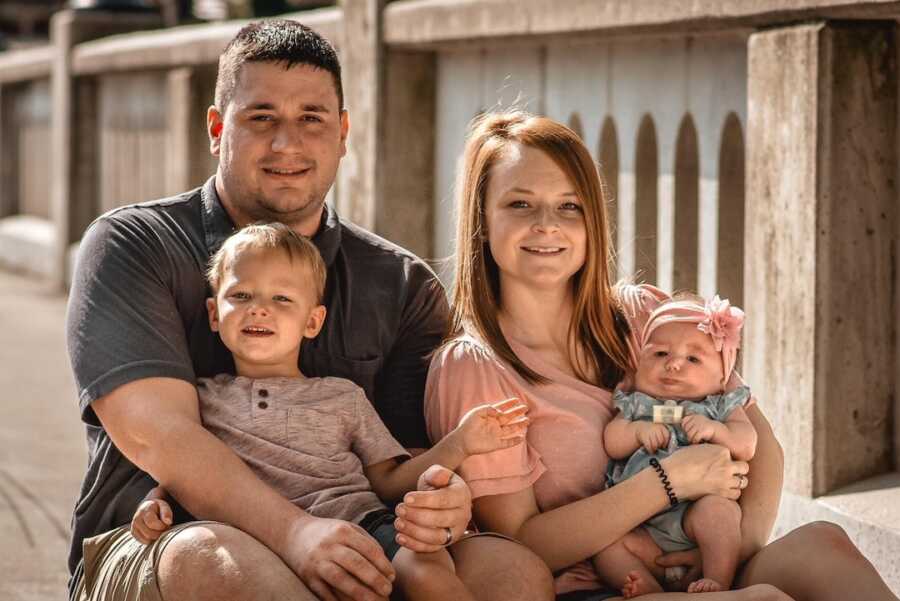 dad sits with son on his lap while mother holds baby girl with nager syndrome