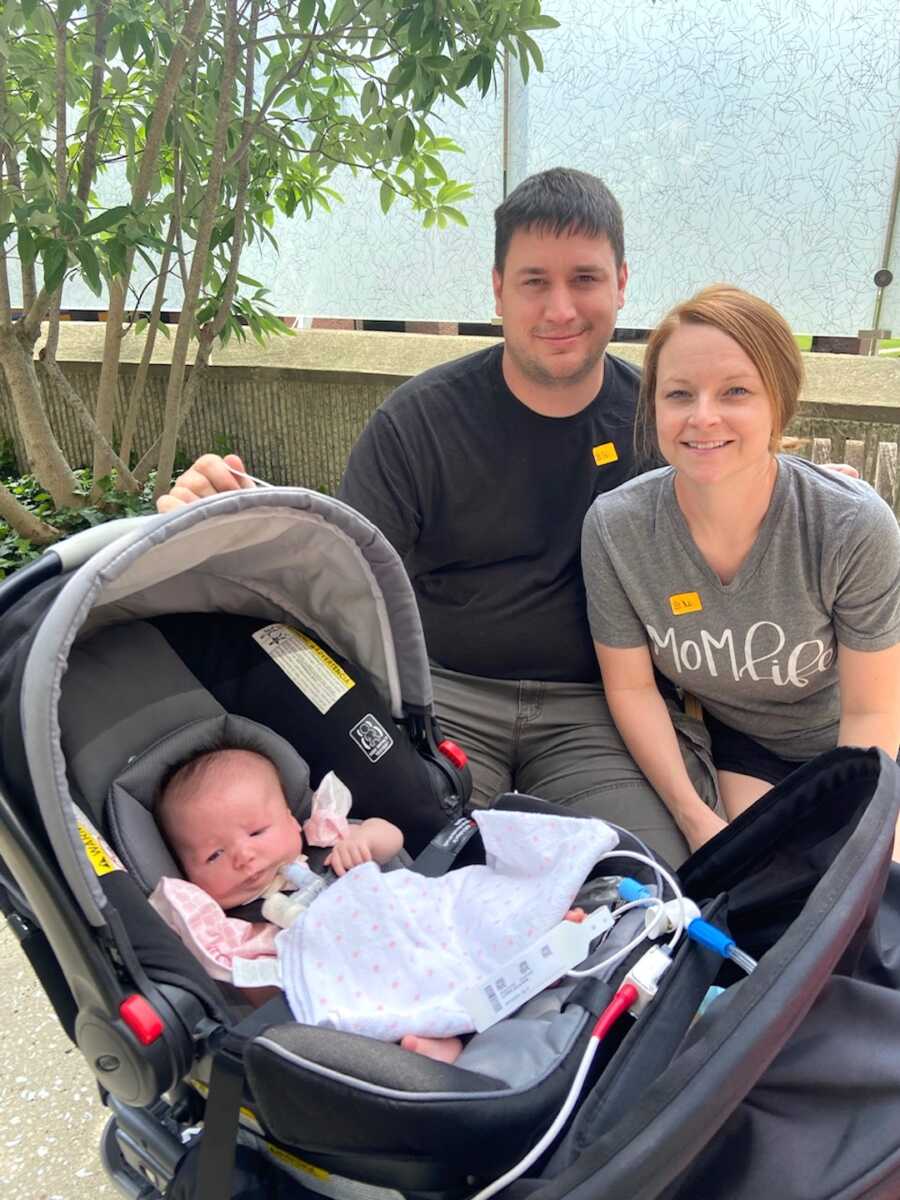 mom and dad sit while their daughter with nager syndrome sits in stroller