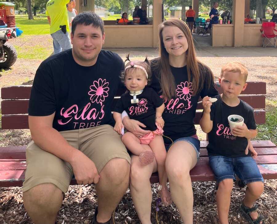 family of four sits on a bench together, wearing matching shirts