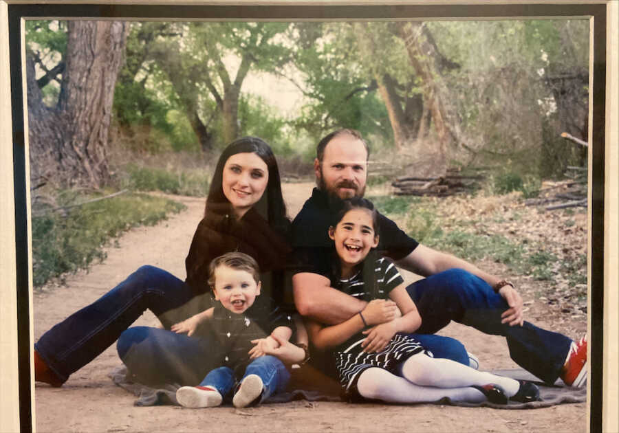 mom and dad sit back to back while the mother holds onto the son and the father holds onto the daughter