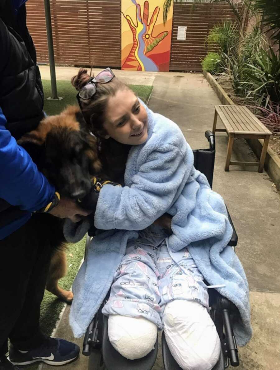 double leg amputee sits in wheelchair and hugs her dog