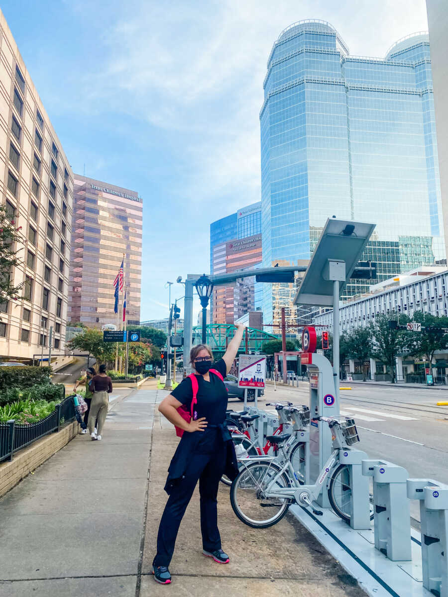 A travel nurse stands outside in a city