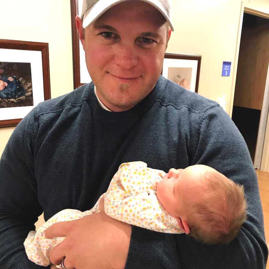 dad holds his adopted baby girl in his arms