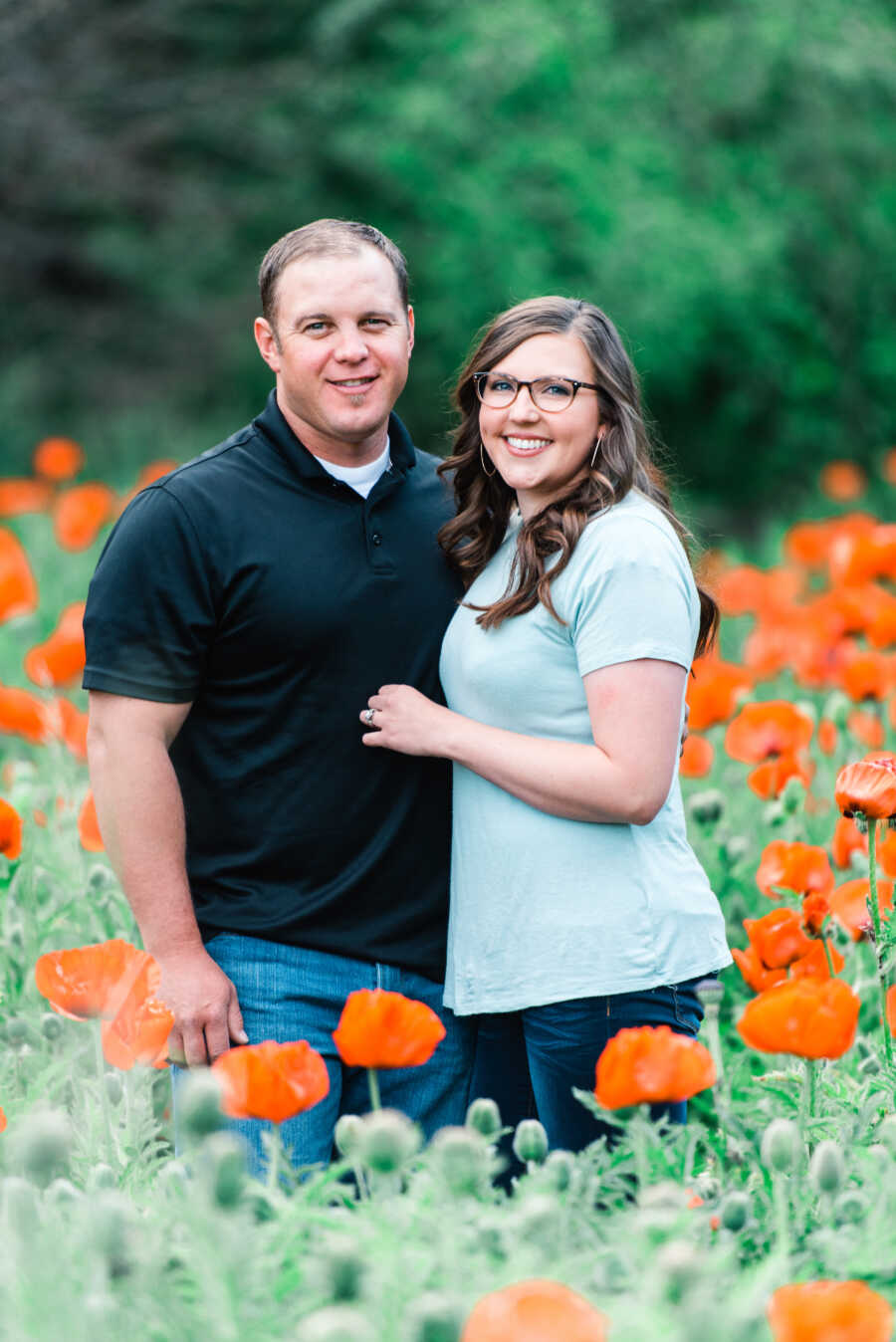 couple poses smiling while in a field of flowers