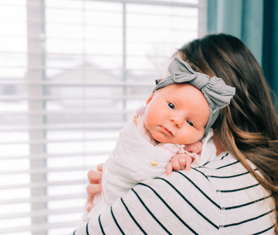 mom holds adopted baby girl over her shoulder