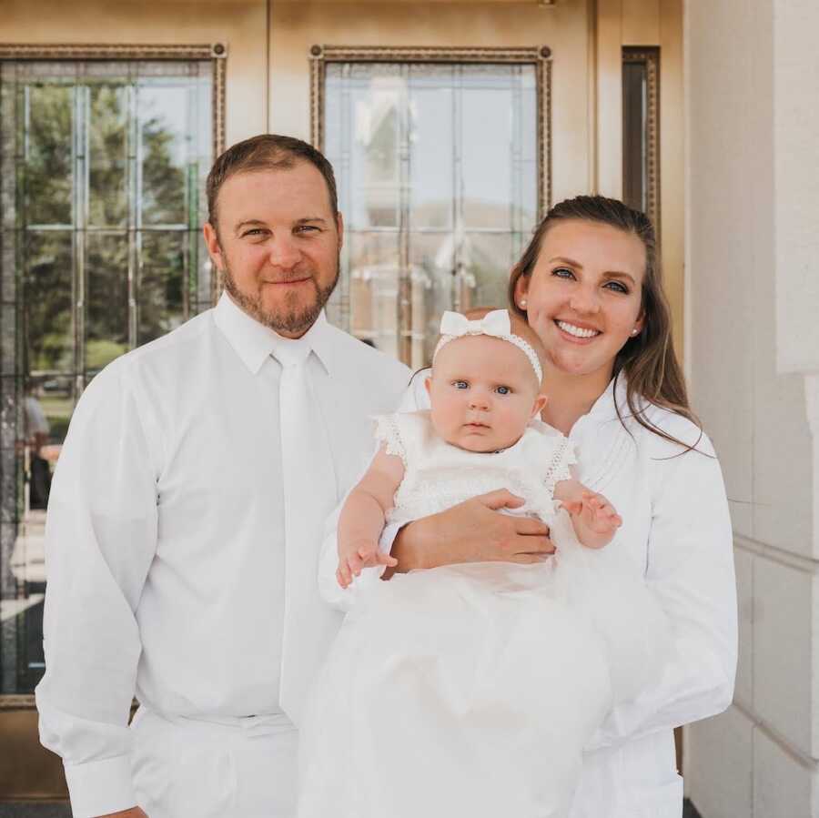 adoptive parents hold their daughter, all in white