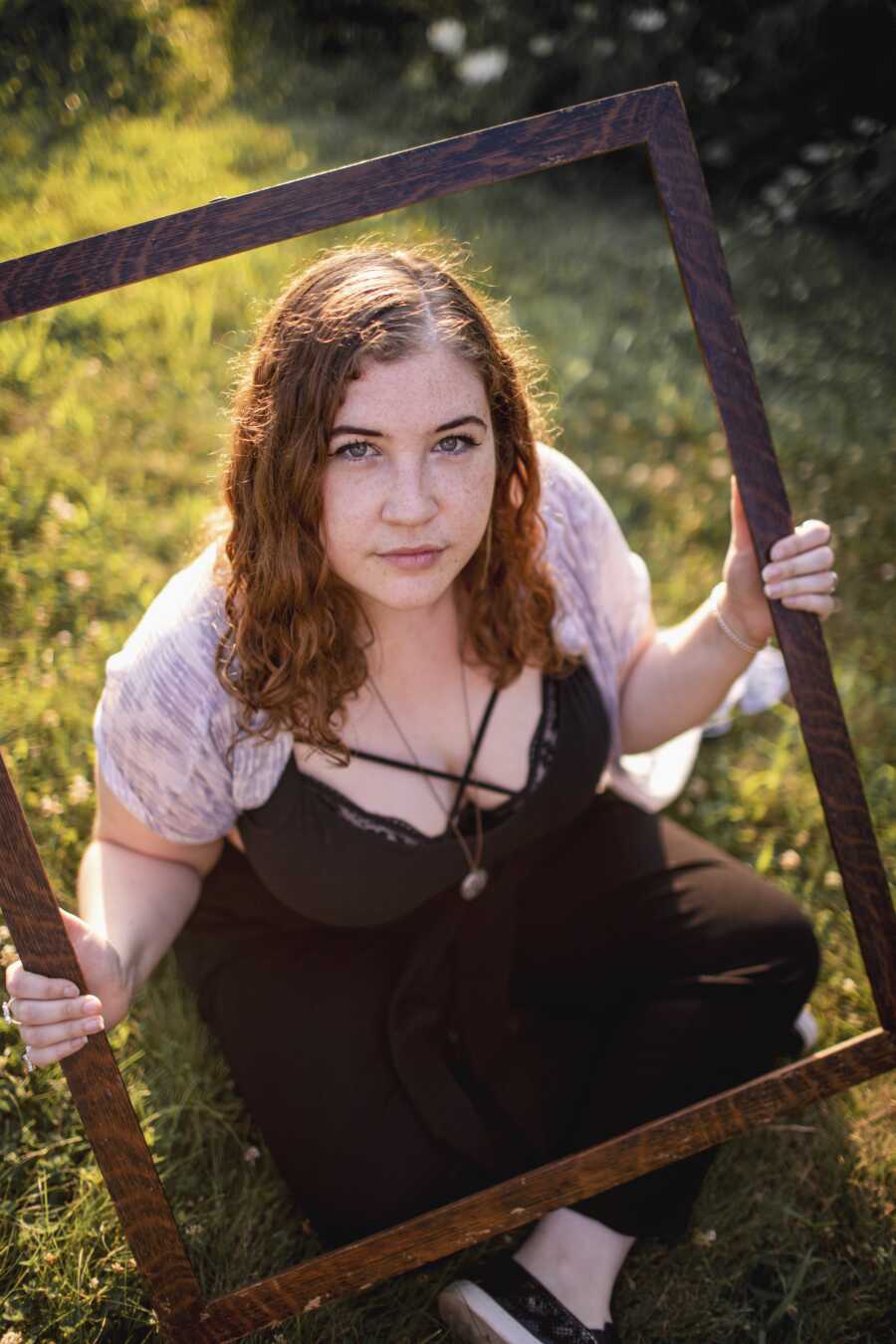 person sitting on the grass, looking up through a picture frame