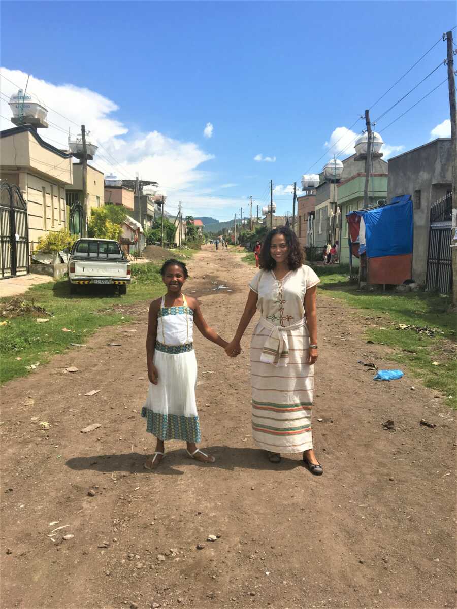 Adoptive mother holding her daughter's hand wearing traditional Ethiopian clothes in the streets of Ethiopia