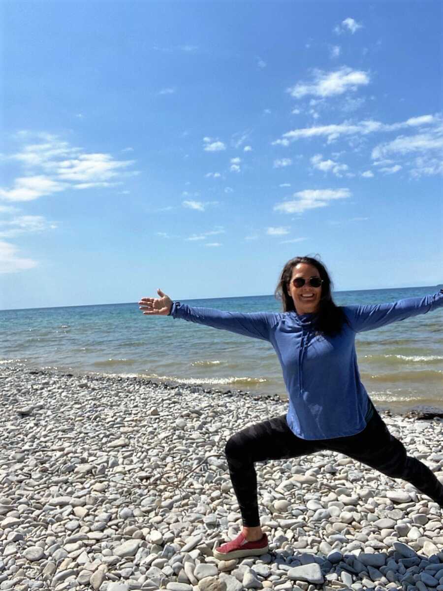 woman doing yoga on a beach in front of water