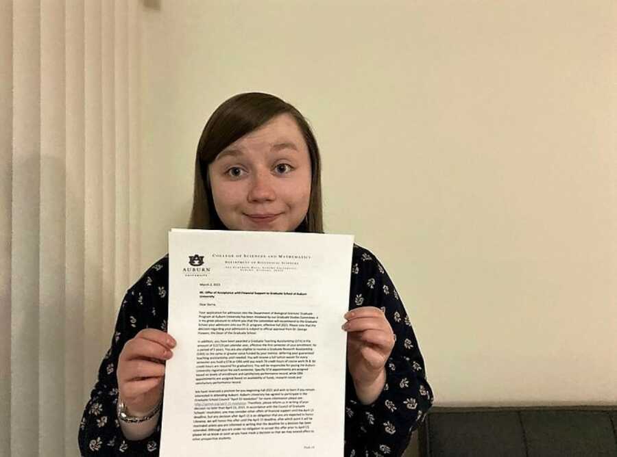 woman with chronic illness holding her phd acceptance