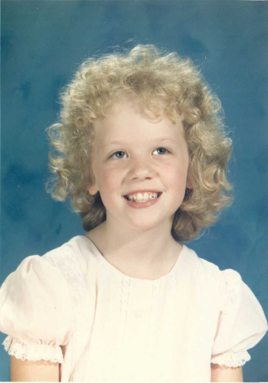 A little girl smiles for a school portrait 