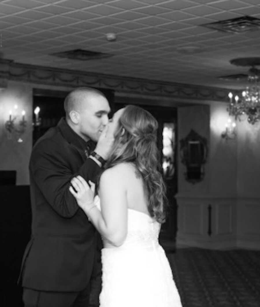 husband holds his wife's face giving her a kiss on their wedding day